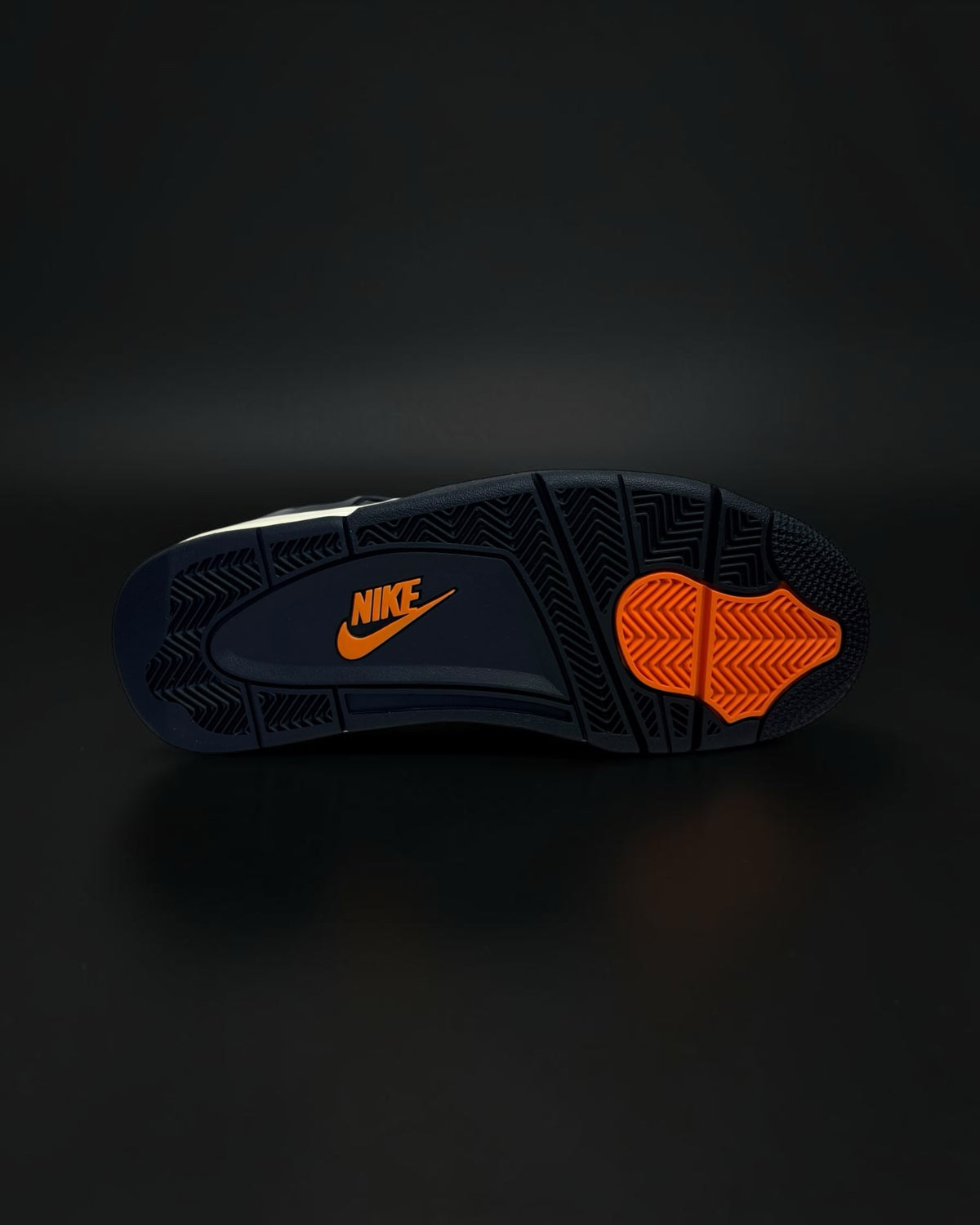 Suela de zapatilla Saint Krew en color negro con logotipo Nike y detalles en naranja vibrante sobre fondo oscuro