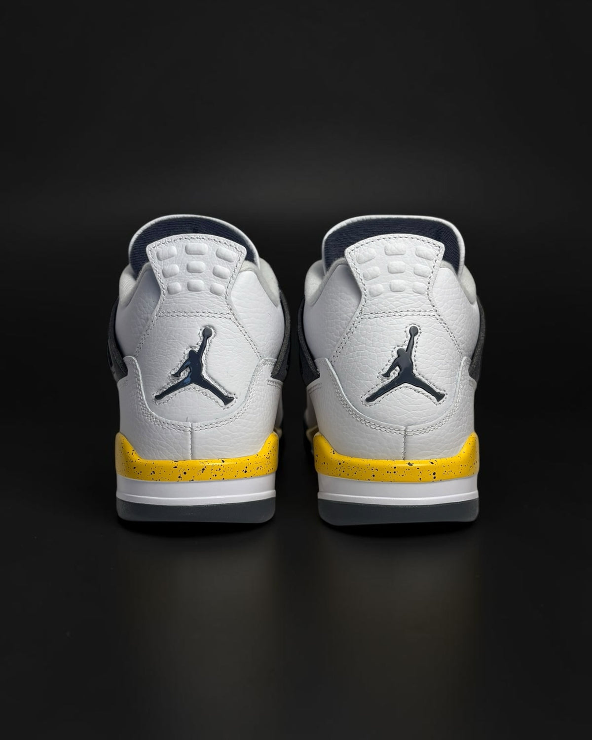 Zapatillas de baloncesto Saint Krew blancas con detalles en azul marino y amarillo moteado, vista trasera.